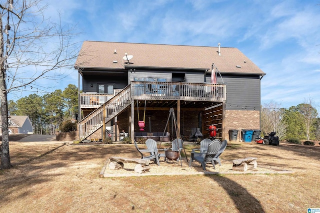 back of property with a wooden deck, a yard, and an outdoor fire pit