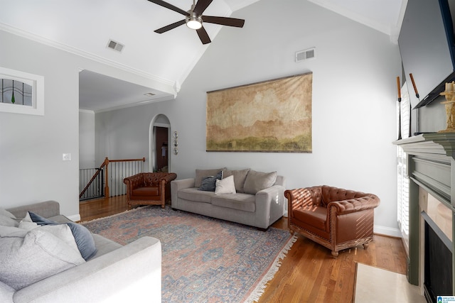 living room featuring high vaulted ceiling, hardwood / wood-style flooring, ornamental molding, and ceiling fan