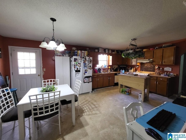 kitchen featuring hanging light fixtures, tasteful backsplash, white fridge with ice dispenser, and a wealth of natural light