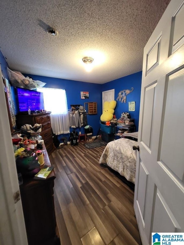 bedroom featuring dark hardwood / wood-style flooring and a textured ceiling