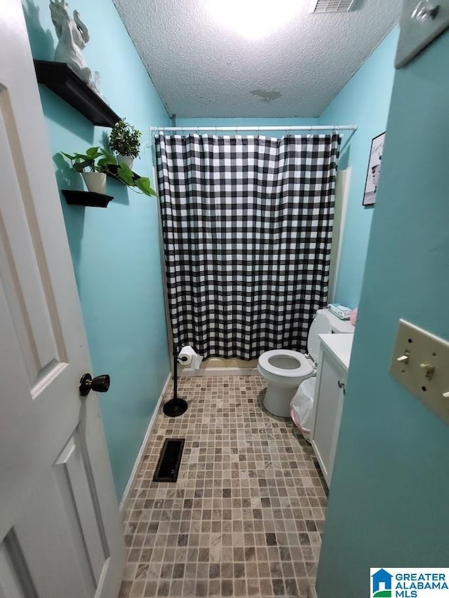 bathroom featuring a shower with curtain, vanity, toilet, and a textured ceiling