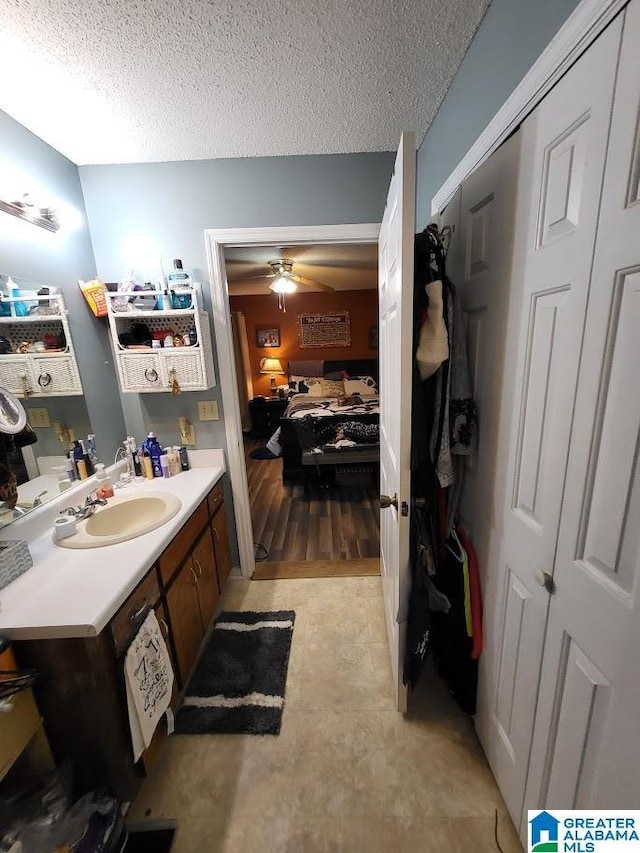 bathroom featuring ceiling fan, vanity, and a textured ceiling