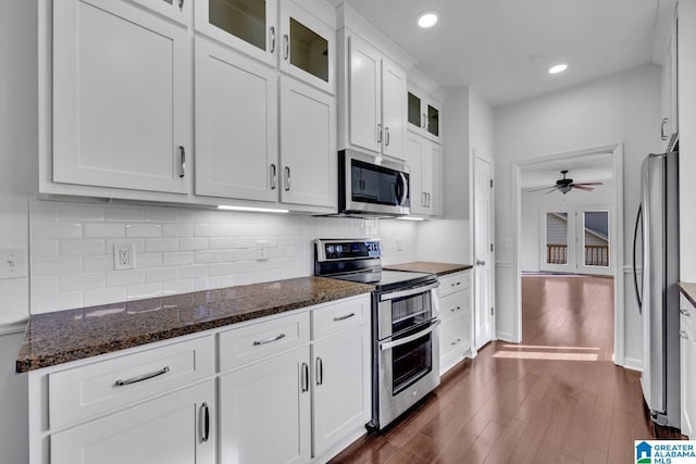 kitchen featuring dark stone countertops, stainless steel appliances, dark hardwood / wood-style flooring, and white cabinets