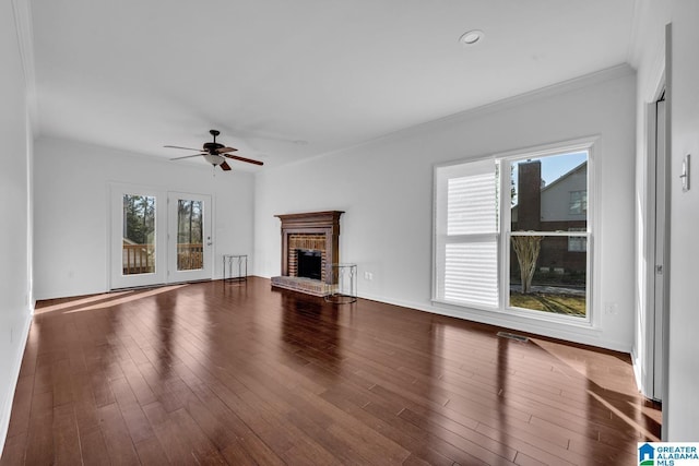 unfurnished living room featuring wood-type flooring, ornamental molding, ceiling fan, and a fireplace