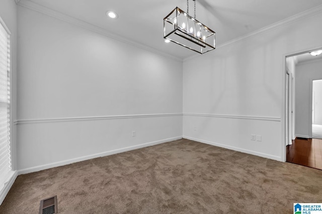 carpeted spare room with ornamental molding and an inviting chandelier