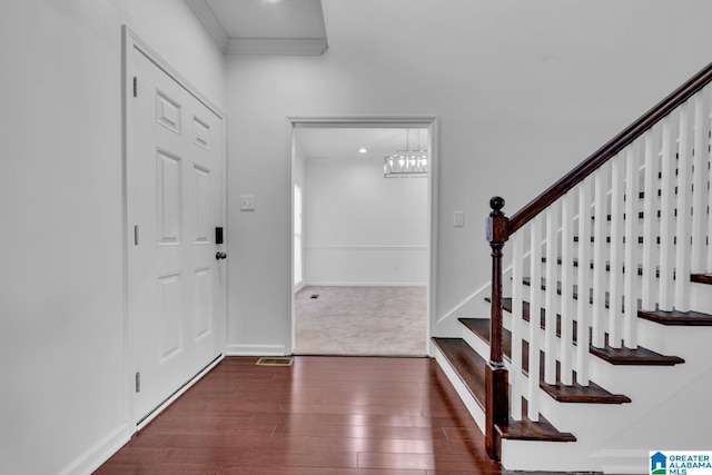 entryway with crown molding, dark hardwood / wood-style floors, and a notable chandelier