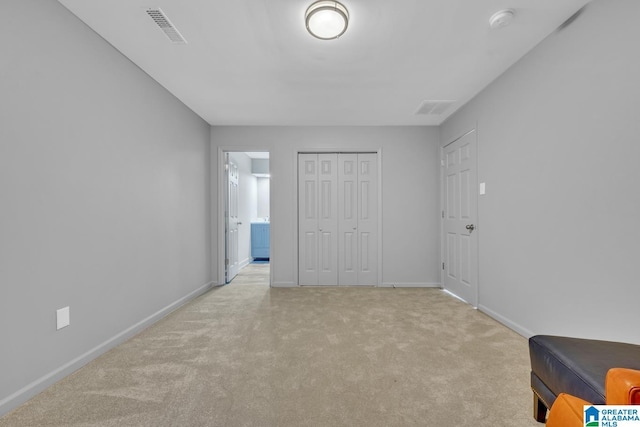 unfurnished bedroom featuring light carpet, ensuite bath, and a closet