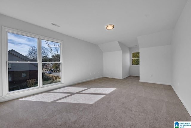 bonus room with lofted ceiling and light carpet