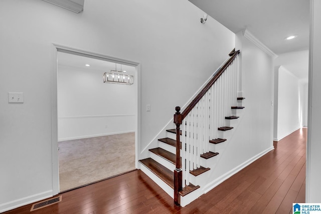 stairs with ornamental molding and hardwood / wood-style floors