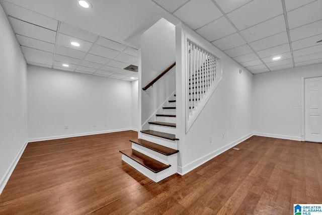 basement with a drop ceiling and wood-type flooring