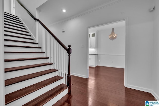 staircase featuring crown molding, wood-type flooring, and a notable chandelier