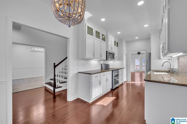 kitchen featuring sink, appliances with stainless steel finishes, pendant lighting, dark stone counters, and white cabinets