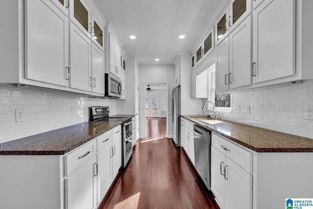 kitchen featuring appliances with stainless steel finishes, sink, dark stone countertops, and white cabinets