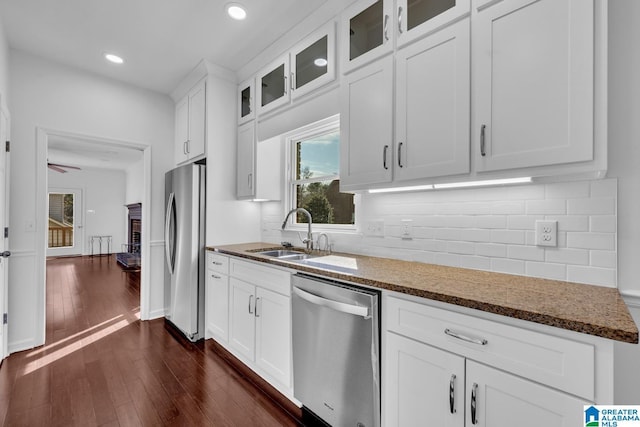 kitchen featuring dark stone countertops, stainless steel appliances, sink, and white cabinets