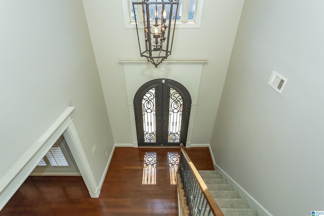 entrance foyer featuring a high ceiling, a healthy amount of sunlight, dark hardwood / wood-style flooring, and french doors