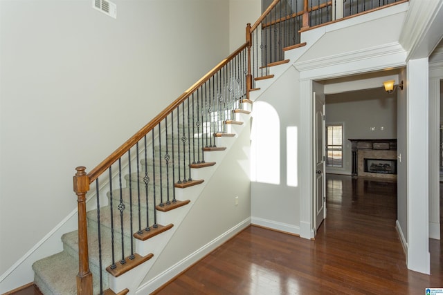 stairway with a towering ceiling and wood-type flooring