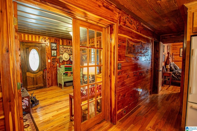 hallway with wood ceiling, wooden walls, and light hardwood / wood-style flooring