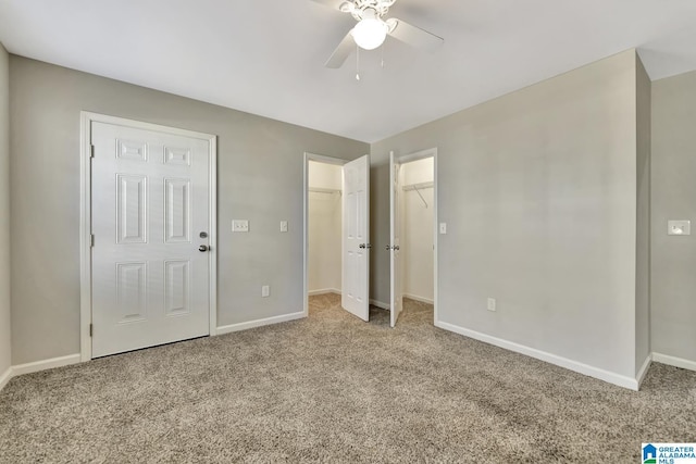 unfurnished bedroom featuring carpet flooring, ceiling fan, and a spacious closet