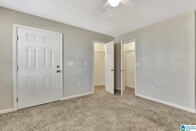 unfurnished bedroom featuring light carpet, a spacious closet, and ceiling fan