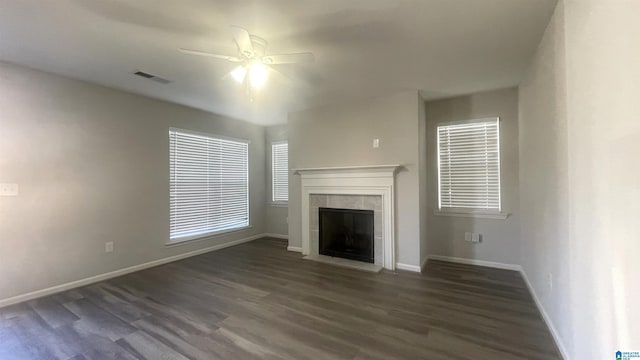 unfurnished living room featuring a tiled fireplace, dark hardwood / wood-style flooring, and ceiling fan