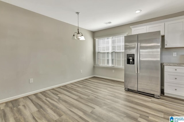 kitchen with stainless steel refrigerator with ice dispenser, an inviting chandelier, hanging light fixtures, light hardwood / wood-style floors, and white cabinets