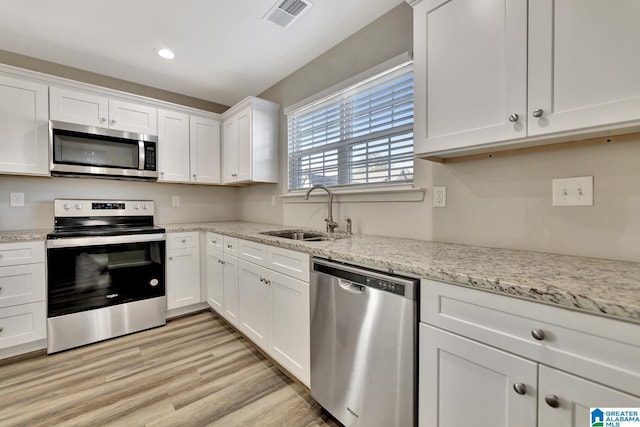 kitchen featuring sink, stainless steel appliances, light stone counters, white cabinets, and light wood-type flooring