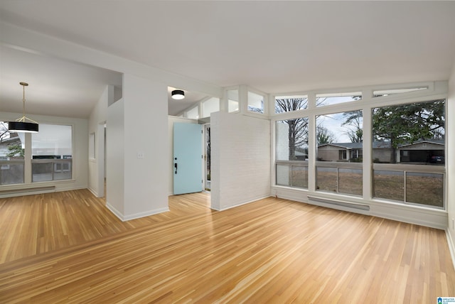 spare room featuring vaulted ceiling, hardwood / wood-style floors, and a baseboard radiator