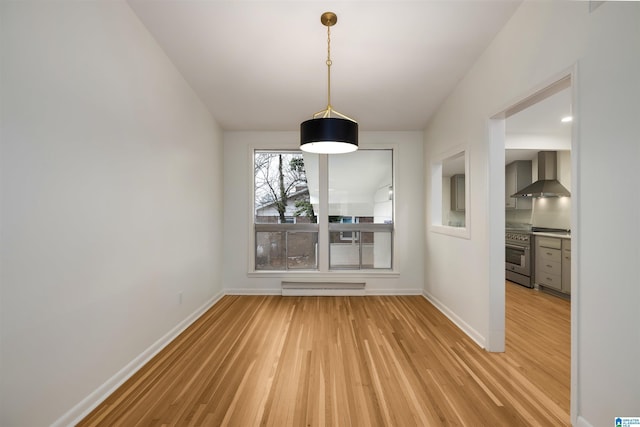 unfurnished dining area featuring a baseboard heating unit and wood-type flooring