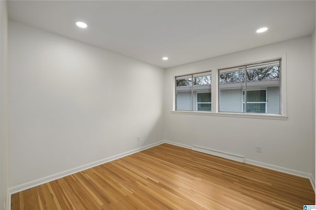 empty room with hardwood / wood-style flooring and a baseboard radiator