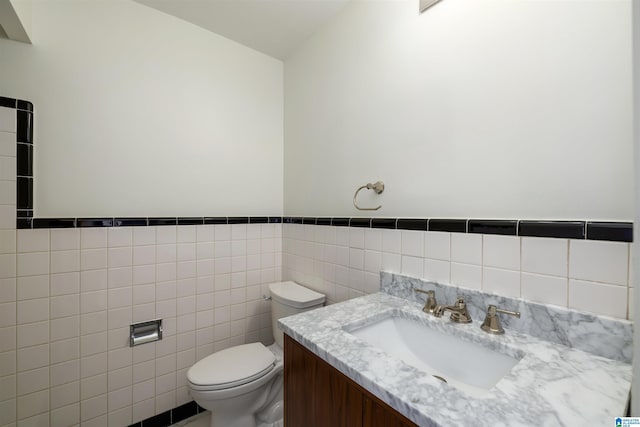 bathroom featuring vanity, tile walls, and toilet