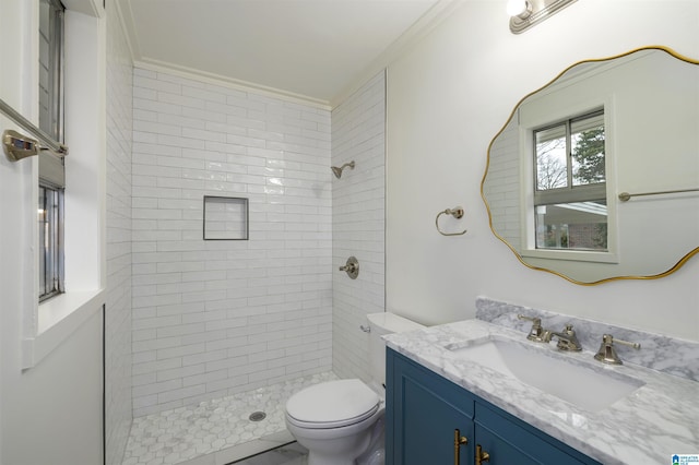 bathroom with vanity, a tile shower, crown molding, and toilet