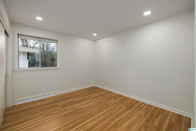 unfurnished room with hardwood / wood-style flooring and a baseboard radiator