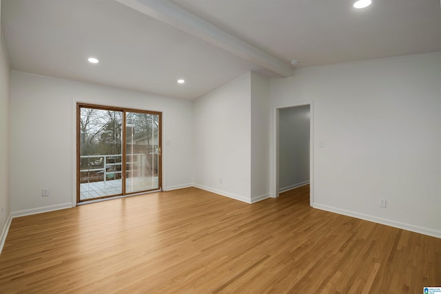 spare room with lofted ceiling with beams and light hardwood / wood-style flooring