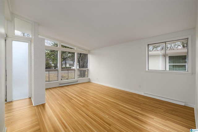 unfurnished room with lofted ceiling, a baseboard heating unit, and light hardwood / wood-style flooring