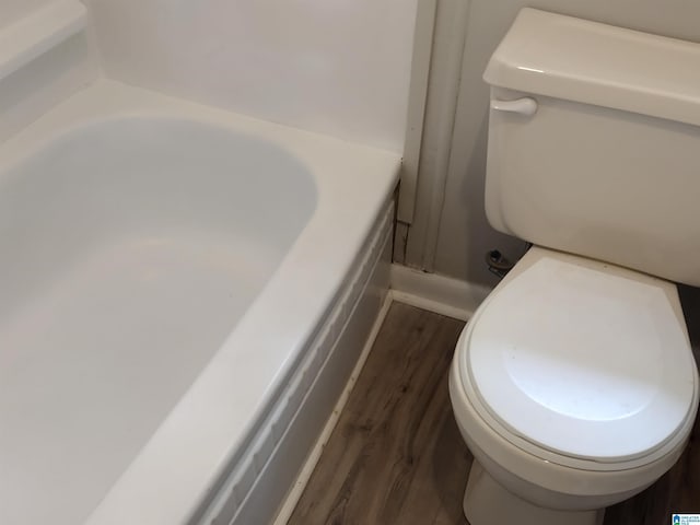 bathroom with wood-type flooring, toilet, and a bath