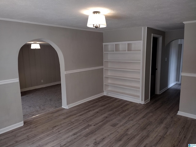 empty room with dark hardwood / wood-style flooring, built in features, and a textured ceiling