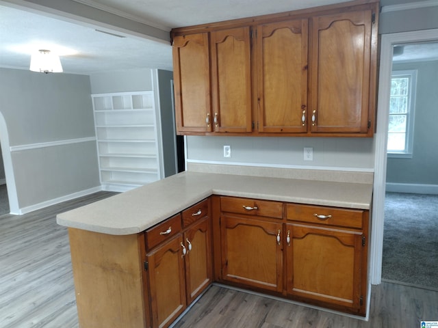 kitchen with ornamental molding, kitchen peninsula, and light hardwood / wood-style floors