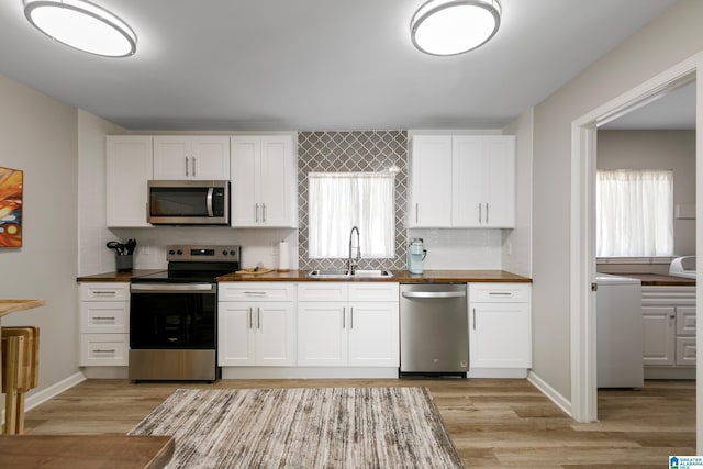 kitchen featuring sink, light hardwood / wood-style flooring, white cabinets, stainless steel appliances, and backsplash