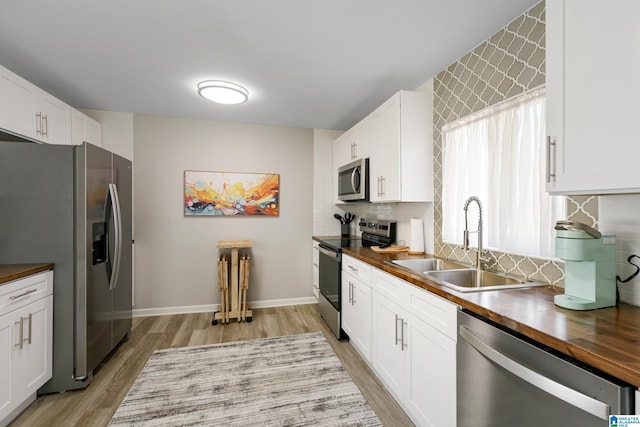 kitchen featuring stainless steel appliances, white cabinetry, and butcher block countertops