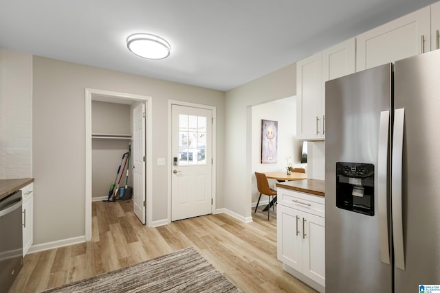 kitchen featuring stainless steel appliances, built in desk, white cabinets, and wood counters