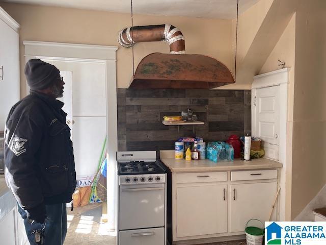 kitchen with premium range hood, range with gas stovetop, and white cabinets