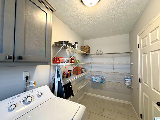 washroom with washer / clothes dryer, a textured ceiling, and cabinets