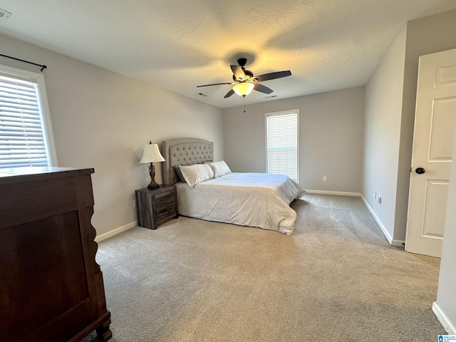 bedroom featuring ceiling fan, light colored carpet, and a textured ceiling