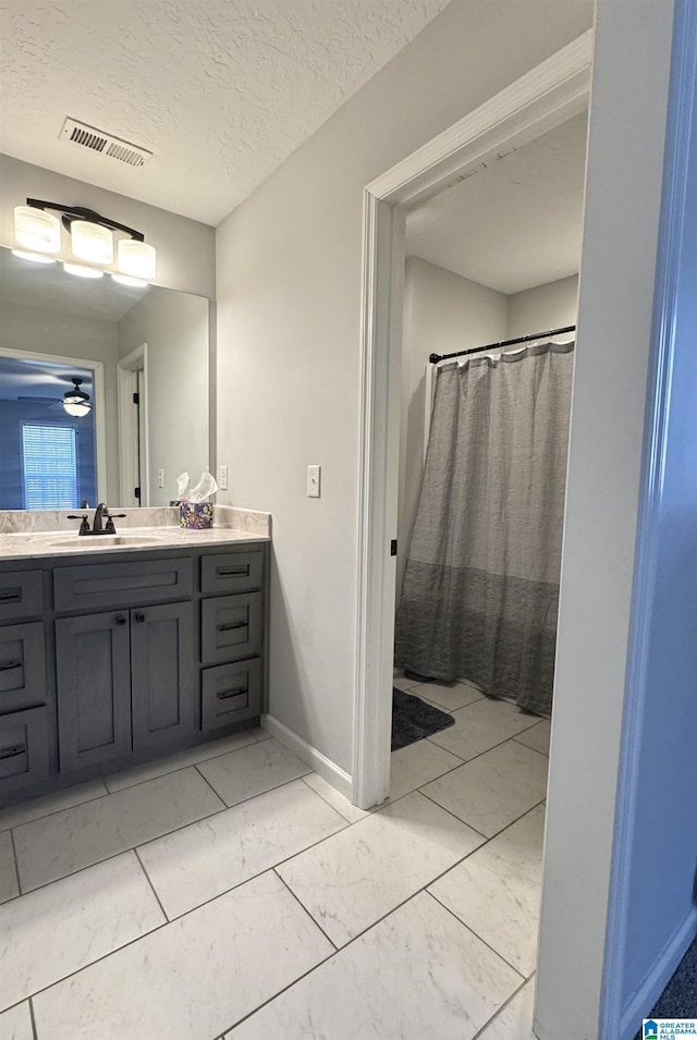 bathroom featuring vanity, ceiling fan, and a textured ceiling