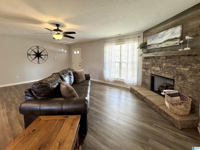 living room featuring dark wood-type flooring, ceiling fan, a fireplace, and a textured ceiling