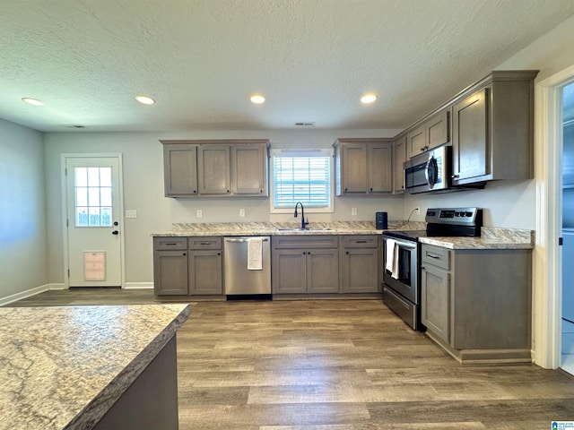 kitchen with sink, hardwood / wood-style flooring, stainless steel appliances, and a textured ceiling