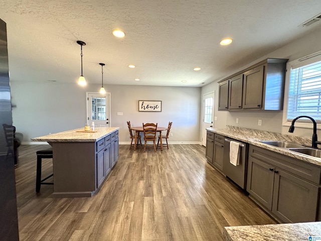 kitchen featuring sink, a center island, hanging light fixtures, a textured ceiling, and dishwasher