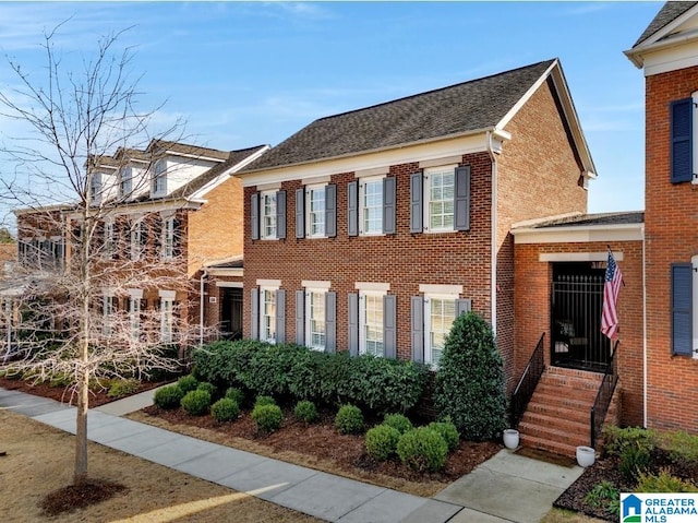 view of front of house featuring a shingled roof and brick siding