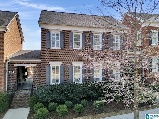 view of front of house featuring roof with shingles and brick siding