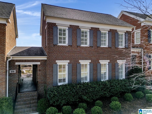 view of front of house featuring brick siding and roof with shingles